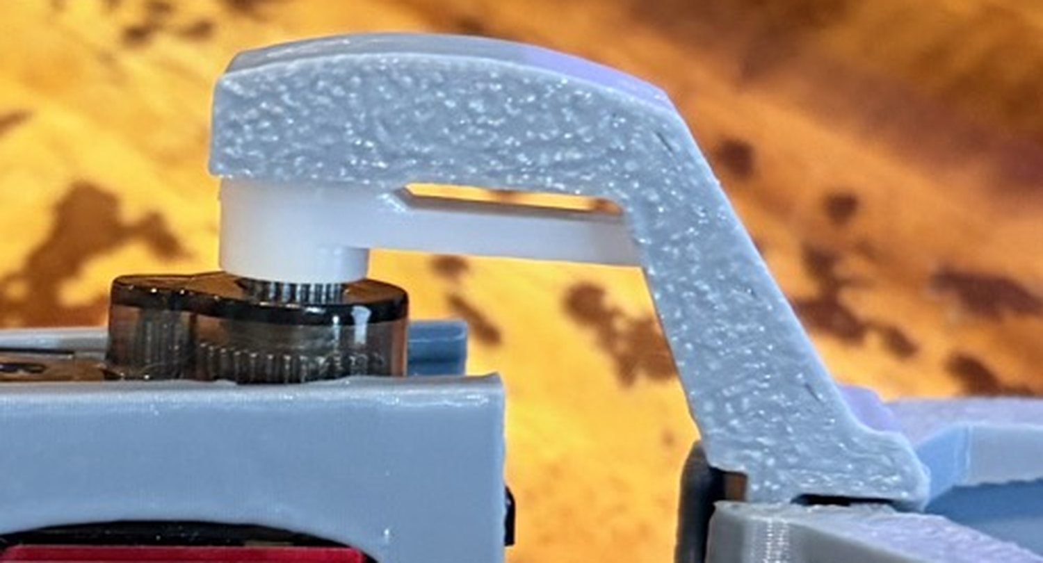 Close-up of the printed knee: a grey hinge arm rests on top of a white servo propeller instead of wrapping around it, with a gap under the arm