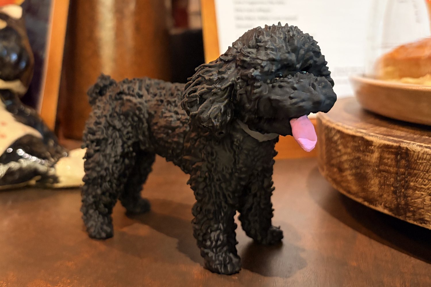 The finished Sumo, a black curly poodle figure painted by hand, standing on a café table