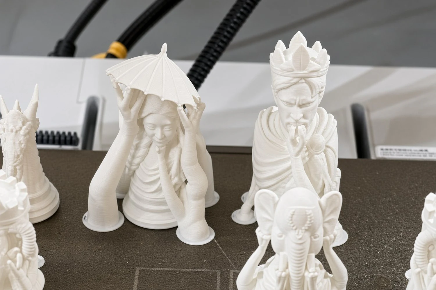 Close up on the printer's build plate: the white queen under her parasol, beside the crowned king